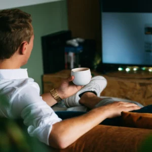 Man holding coffee watching TV.