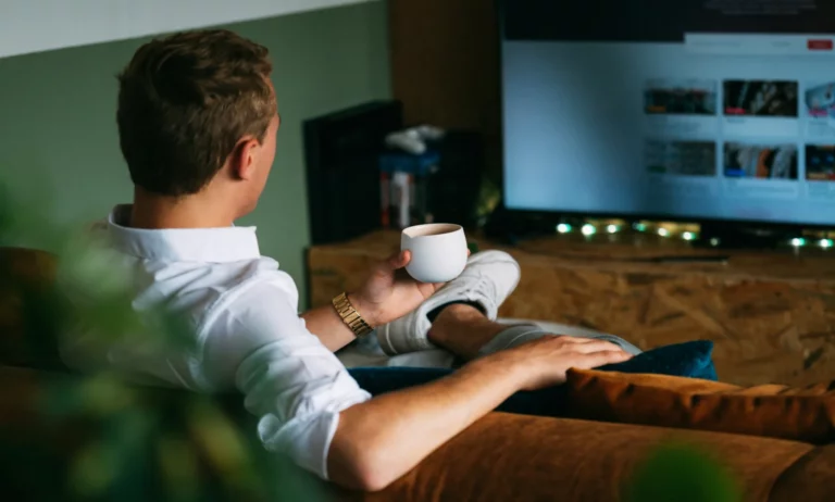 Man holding coffee watching TV.