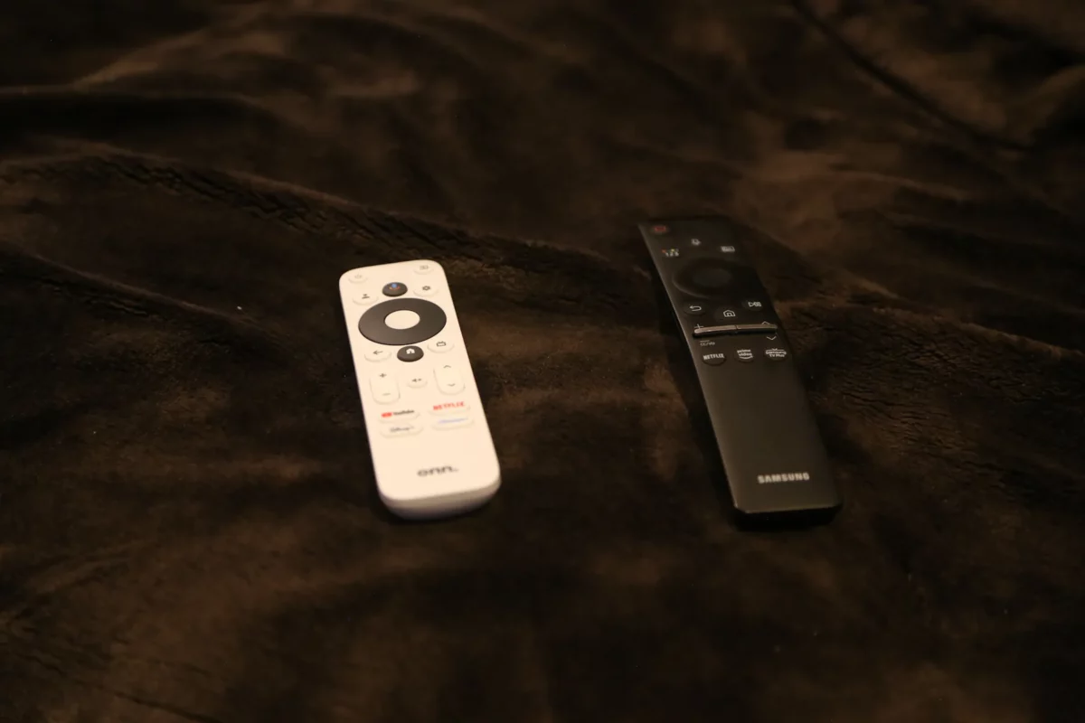 The Onn Google TV Streamer remote next to my black Samsung TV remote